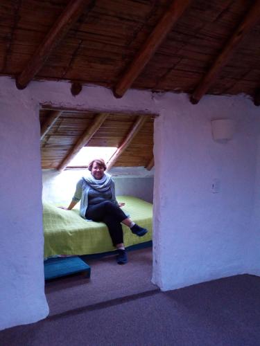 a woman sitting on a bed in a small room at Jardin Colibri RNT 33633 in Guatavita