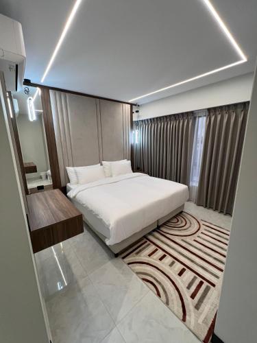 a bedroom with a white bed and a rug at Hodoon Apartments in Amman