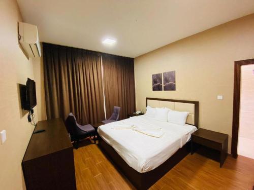 a hotel room with a large bed and a desk at Alpha Suites Salalah in Salalah