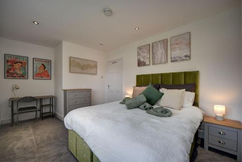 a bedroom with a large bed with a green headboard at The Chislehurst Hideaway in Chislehurst