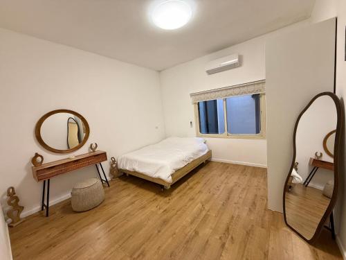 a white bedroom with a bed and a mirror at Cozy peak suite in Majdal Shams