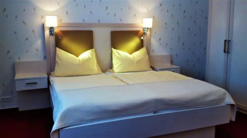 a bedroom with a large bed with two lamps on it at Hotel-Garni Herzog in Loher Ostmark