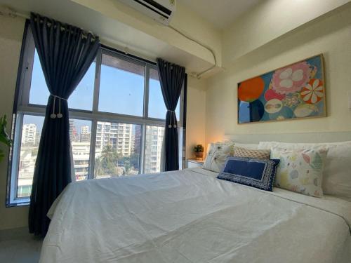 a bedroom with a white bed and a large window at Sheetal Vaibhav 902 in Mumbai