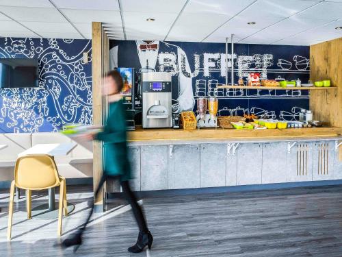 a person walking past a counter in a kitchen at Ibis Budget Fréjus St Raphaël centre plages gare TGV in Fréjus