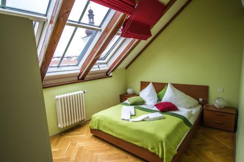 a bedroom with a bed with green sheets and windows at Ruterra Red Roofs View With Garage in Prague