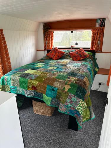 a bedroom with a bed with a colorful quilt at The Bru Bus in Maybole