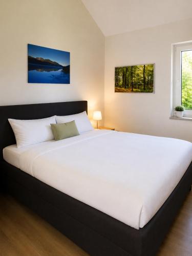 a large white bed in a bedroom with a window at Ferienhäuser Seetraum - Premium Card inklusive in Weissensee