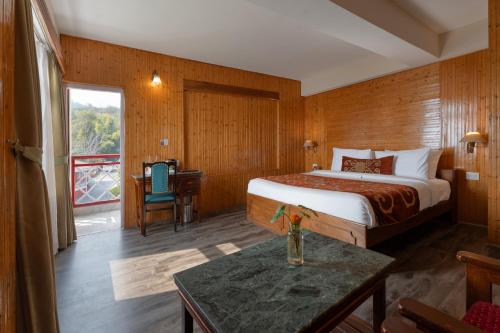 a bedroom with a bed and a table in a room at Summit Tashi Ghang Heritage Resort in Pelling