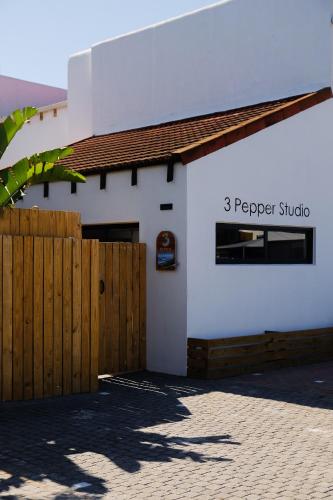 a white building with a wooden fence in front at 3 Pepper Street by African Perfection in Jeffreys Bay