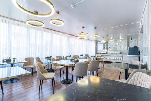 a restaurant with tables and chairs and windows at Oscar Hotel by AG Hotels Group in Almaty