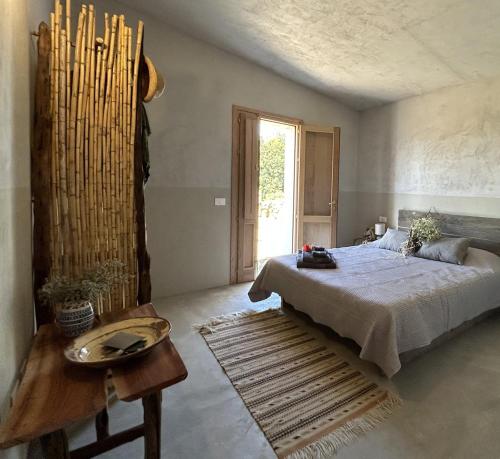 a bedroom with a bed and a table and a window at Stazzu Pittorra per 4 persone in Barrabisa