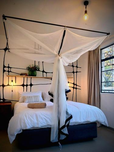 a bedroom with a large bed with a canopy at Birdsong Bungalow in Livingstone