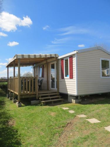 a tiny house with a porch and a deck at Hebergement dans un Domaine à Litteau in Litteau