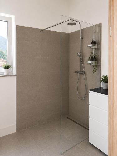 a shower with a glass door in a bathroom at Ferienhäuser Seetraum - Premium Card inklusive in Weissensee