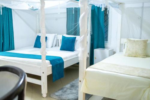 two beds in a room with blue curtains at Cosy Garner Haven Watamu in Watamu