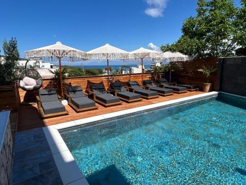 a swimming pool with lounge chairs and umbrellas next to a swimming pool at Vila Jeti in Ksamil