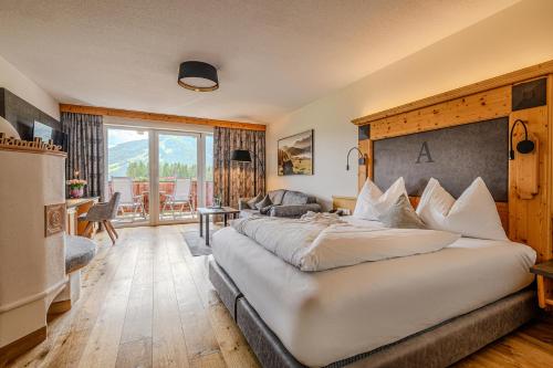 a bedroom with a large bed and a living room at Hotel Alpina Wellness & Spa Resort in Kössen