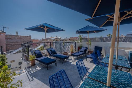 a patio with blue chairs and tables and umbrellas at Riad Blue Berry & SPA in Marrakesh