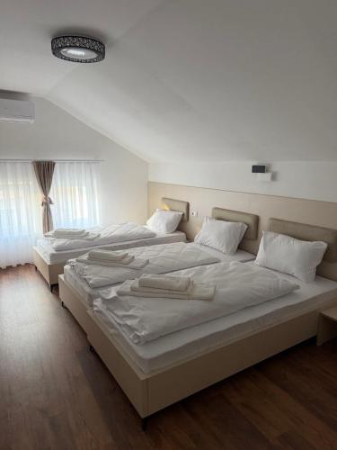 a bedroom with two beds with white sheets at Hotel Joana in Prizren