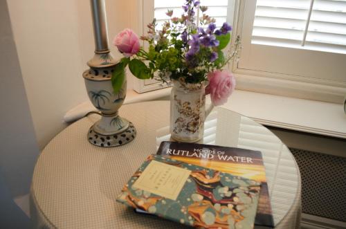 a table with a vase of flowers and a book at The Hollies Bed and Breakfast in Uppingham