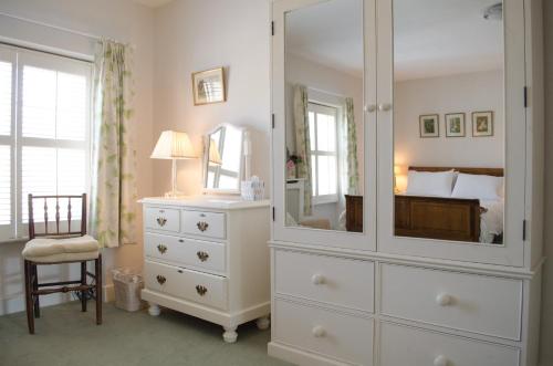 a bedroom with a large white dresser and a mirror at The Hollies Bed and Breakfast in Uppingham