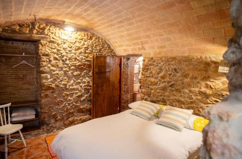 a bedroom with a bed in a stone wall at Can Gandaia in Viladamat