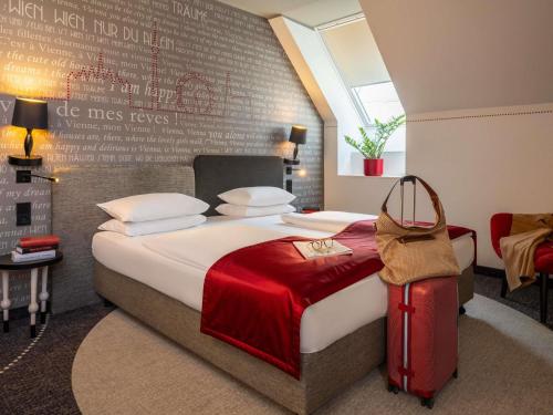 a bedroom with a bed with a red suitcase at Mercure Vienna First in Vienna