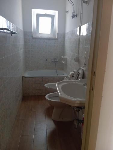 a bathroom with three sinks and a bath tub and a window at Appartamento vacanza Penne in Penne