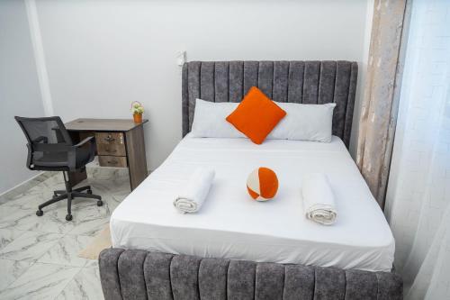 a bed with orange and white pillows and a desk at Malindi White in Malindi