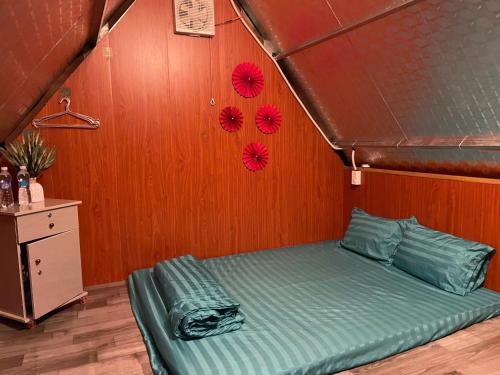 a bed in a room with a wooden wall at Homestay Vườn Cam in Kon Von Kla