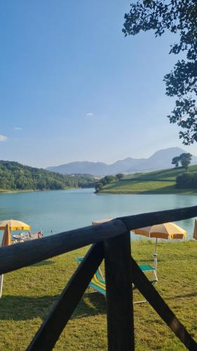 a fence in front of a lake with umbrellas at Agriturismo Vallonga in Poggio San Vicino