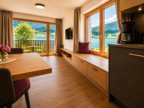 a kitchen with a table and a view of the water at Der Kaerntnerhof am Weissensee, SeeHotel & SeeApartments direkt am See in Weissensee