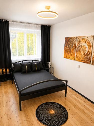 a black bed in a room with a window at Romance Apartments in Panevėžys