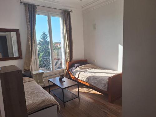 a bedroom with two beds and a large window at Appartement Familial - Saint-Lazare à moins de 15 min in Bois-Colombes