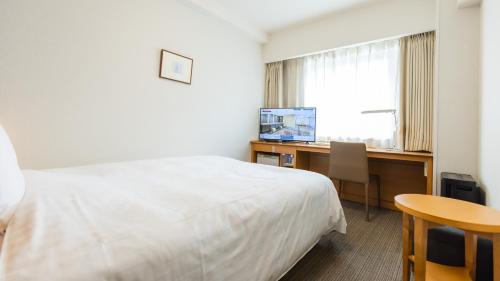 a hotel room with a bed and a desk and a window at Richmond Hotel Sapporo Ekimae in Sapporo