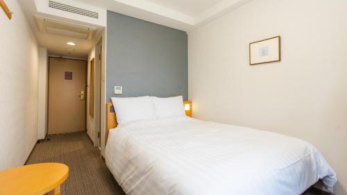 a bedroom with a large white bed and a table at Richmond Hotel Sapporo Ekimae in Sapporo