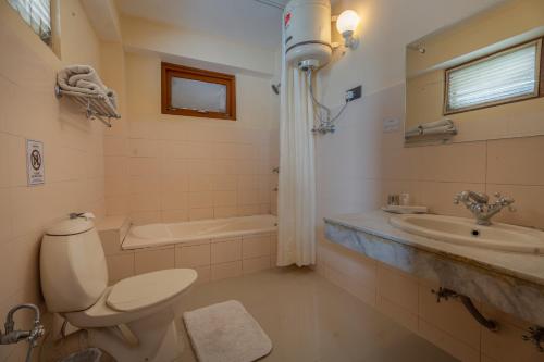 a bathroom with a toilet and a sink and a tub at Summit Tashi Ghang Heritage Resort in Pelling