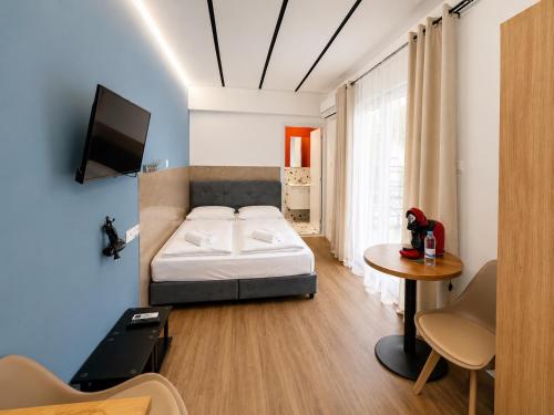 a bedroom with a bed and a table and a tv at Modern Studio 8 Balcony Kitchenette Bathroom in Limassol