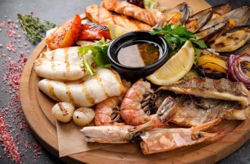 a plate of seafood and vegetables on a table at CARIBBEAN DREAMS Apartment & Villas - OCEAN VIEW - POOL - BBQ in Punta Cana