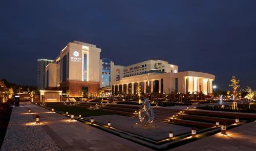 un grand bâtiment avec des lumières devant lui la nuit dans l'établissement Hyatt Regency Tashkent, à Tachkent