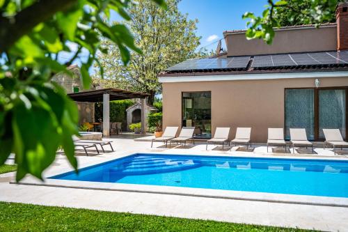 a swimming pool with chairs and a house at Villa Ferlini in Central Istria with private 10000 m2 garden, wellness & family activities on plot in Svetvinčenat