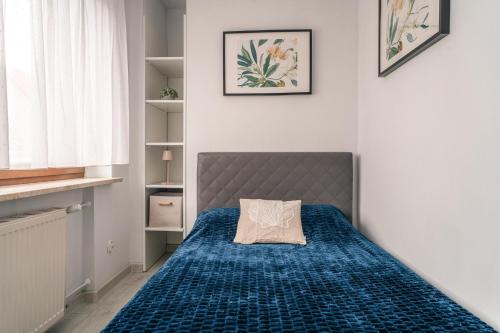 a bedroom with a bed with a blue bedspread at Szafir Kuźnica - Apartamenty 4 min od plaży in Kuźnica