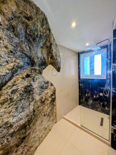 a bathroom with a large rock wall at Madalenas B&B in Pelekas