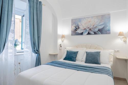 a white bedroom with a bed with blue curtains at Domus Almaré in Minori