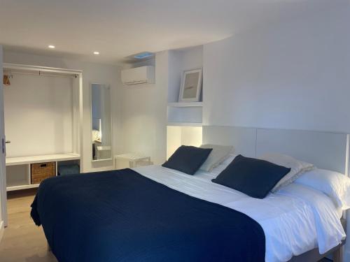 a bedroom with a large bed with two blue pillows at Apt Es Poal - Des Puig in Cadaqués