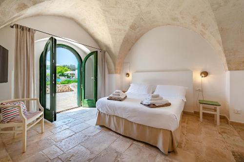 a bedroom with a bed and a large window at Masseria Gorgognolo in Ostuni