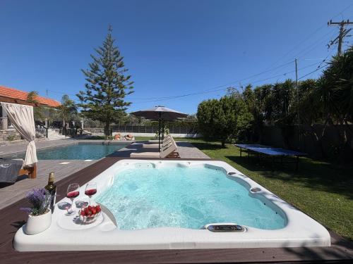 a hot tub with wine glasses and a pool at S&T VILLA in Haraki