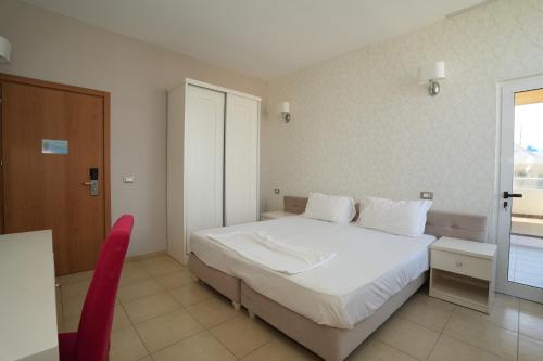 a bedroom with a white bed and a red chair at Sun Hotel in Durrës