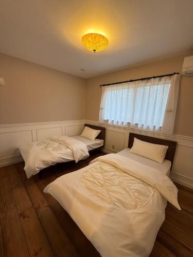 two beds in a room with a window at Maison de L in Hokuto