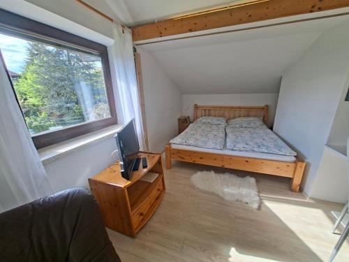 a bedroom with a bed and a desk and a window at Kleines Apartment in Pertitschach
